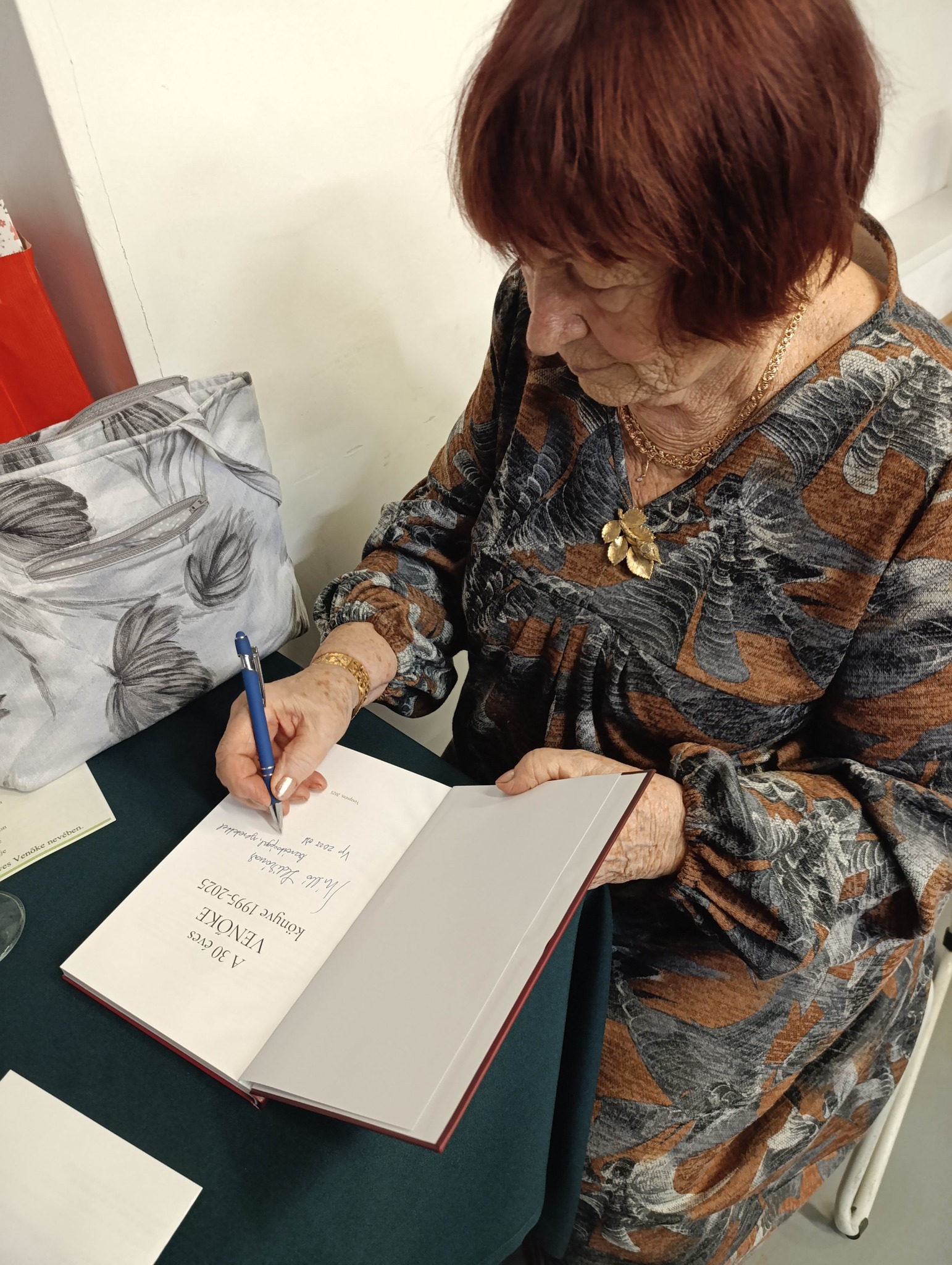 Huszár Józsefné Júlia dedikálja a VENŐKE jubileumi kötetet